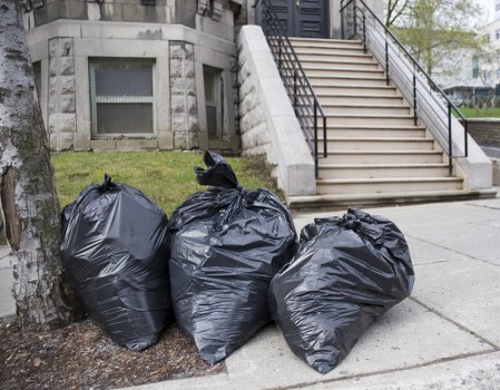 Staff member wearing PPE and handling segregated waste for disposal